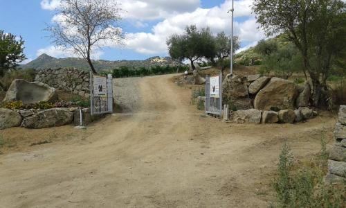 a dirt road with a gate and rocks on it at Agriturismo Locoe in Oliena