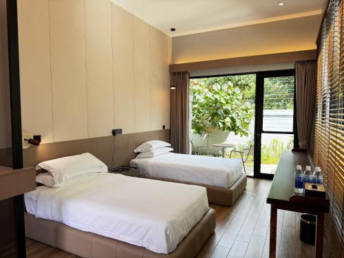 two beds in a hotel room with a window at Tambuna Retreat ,TAMBUN ,IPOH in Tambun