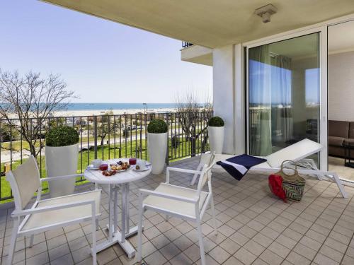 リミニにあるMercure Rimini Lungomareのテーブルと椅子と海のあるパティオ