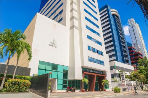 サルバドールにあるBahia Businees salvadorのヤシの木が前に立つ背の高い白い建物