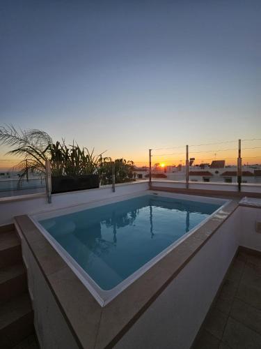 una piscina con un tramonto sullo sfondo di Ático costa de la luz a Conil de la Frontera