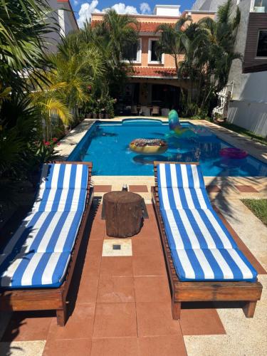 two chairs and a table in front of a swimming pool at Magnifica Villa Palmeras luxurious 4 Br 6 Bds 4 Ba private pool lagoon front super fast Wifi in Cancún