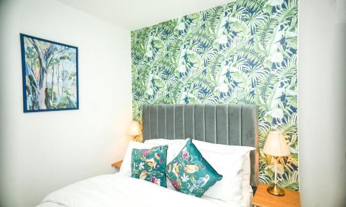 a bedroom with a bed with a tropical wallpaper at Windsor and Heathrow Stay Comfort & Free Parking in Slough