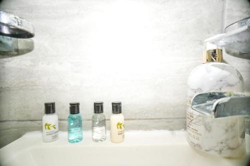four bottles of soap sitting on a bathroom sink at Windsor and Heathrow Stay Comfort & Free Parking in Slough