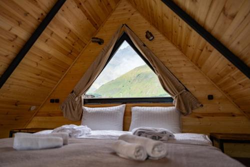 a bedroom with a bed with a large window at Outdoor Cottages Kazbegi in Kazbegi