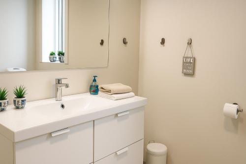 Un baño blanco con lavabo y espejo. en Havhuset I Øster Hurup - i byen, ved stranden, en Øster Hurup