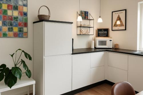 a kitchen with white cabinets and a microwave at Havhuset I Øster Hurup - i byen, ved stranden in Øster Hurup