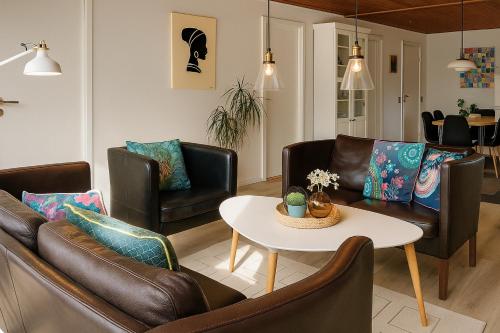 a living room with leather chairs and a table at Havhuset I Øster Hurup - i byen, ved stranden in Øster Hurup