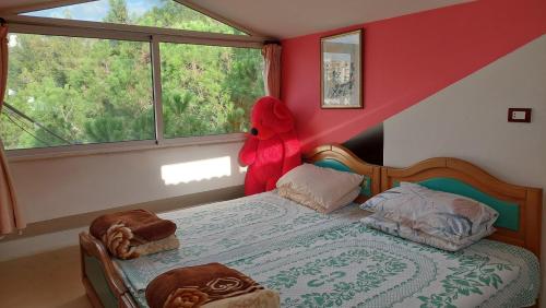 a bedroom with a red teddy bear standing next to a bed at Arcadia Guesthouses - Ghazir, Lebanon in Ed Dkârîne