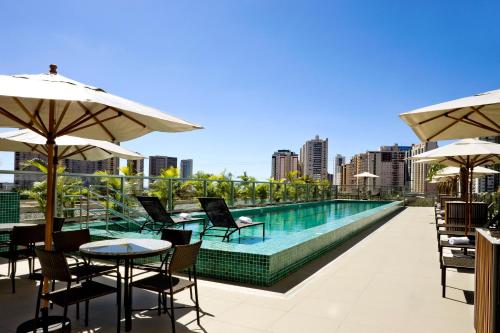 a swimming pool with chairs and tables and umbrellas at Intercity Brasilia Led Aguas Claras in Brasilia
