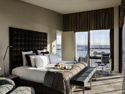 オークランドにあるPullman Auckland Hotel & Apartmentsの大きなベッドと机があるホテルの部屋