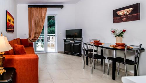 a living room with a table and a tv at Niki Apartments in Chrysi Ammoudia