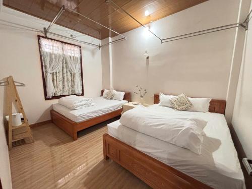 a bedroom with two beds and a window at A Tứng House Bản Giốc in Trùng Khánh
