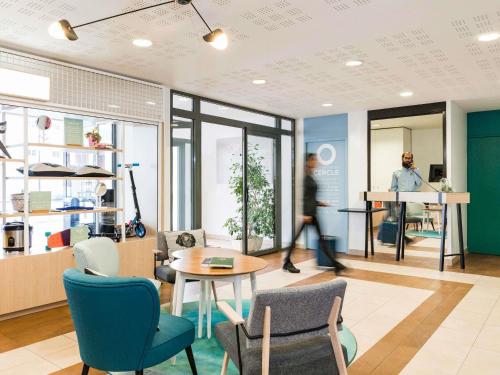 a room with chairs and a table and a person at Aparthotel Adagio Access Paris Clamart in Clamart