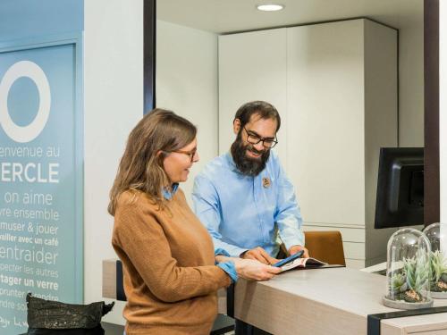 a man and a woman standing at a counter at Aparthotel Adagio Access Paris Clamart in Clamart