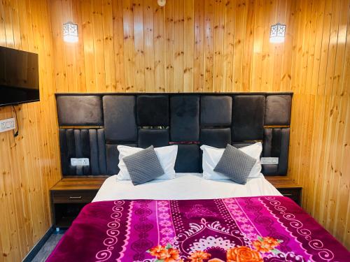 a bedroom with a large bed with a purple blanket at 3 H Homestay in Mussoorie