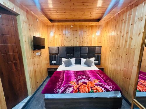a bedroom with a bed in a wooden wall at 3 H Homestay in Mussoorie