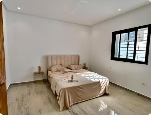 une chambre avec un grand lit dans une pièce blanche dans l'établissement Villa Bianca, à Sidi Jedidi