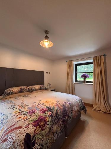 a bedroom with a bed with a floral bedspread and a window at The Barn, Walworth Demesne in Ballykelly