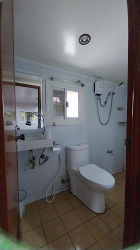 a white bathroom with a toilet and a sink at Beachfront Aircon Modern Bahay Kubo for 10 pax in Caba