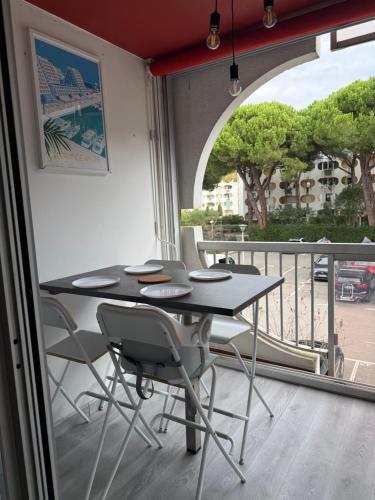 ein Tisch und Stühle in einem Zimmer mit Balkon in der Unterkunft Studio cv 4p, parking privée cosy design in La Grande-Motte