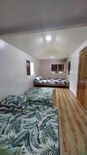 two beds in a room with a green and white blanket at Beachfront Aircon Modern Bahay Kubo for 10 pax in Caba