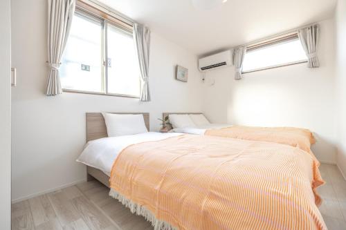 two beds in a bedroom with two windows at Skytree House Oshiage New 3-story Villa, 2 Showers, 2 Toilets, 4 Rooms, 3 min walk to Oshiage Station in Tokyo