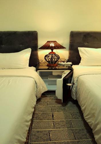 a bedroom with two beds and a table with a lamp at Dar Noureddine in Lalla Takerkoust