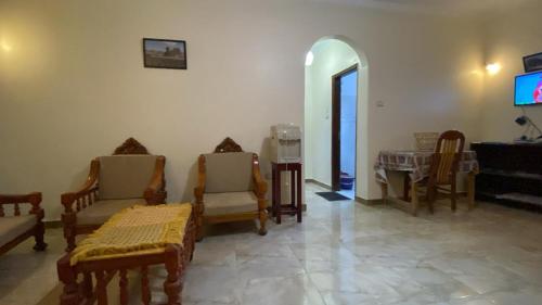 ein Wohnzimmer mit Holzstühlen und einem TV in der Unterkunft Tibs mountain view in Al Aqālitah