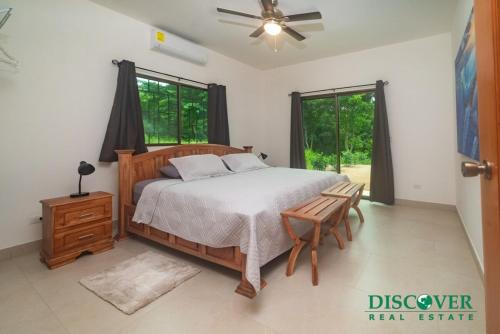 a bedroom with a bed and a chair and windows at Nica Nest 3Br Eco Home Escamequita, NI in San Juan del Sur