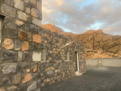 a brick building with mountains in the background at بيت دار السوداء in Dār Sawdāʼ