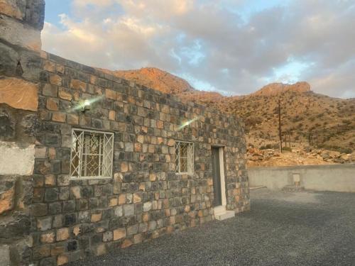 a brick building with a window and mountains in the background at بيت دار السوداء in Dār Sawdāʼ