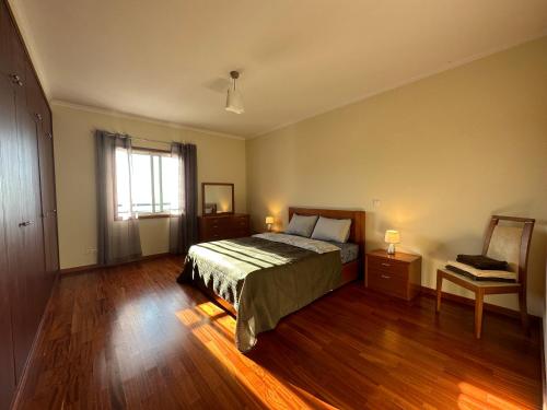 a bedroom with a bed and wooden floors and a window at Forum Madeira near beach Formosa in Funchal