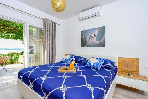 a bedroom with a blue bed and a large window at Holiday Villa Noa in Orebić