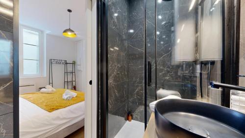 een badkamer met een wastafel en een douche met een bed bij expat renting - Le Cyrano - Hyper centre - Wifi in Toulouse