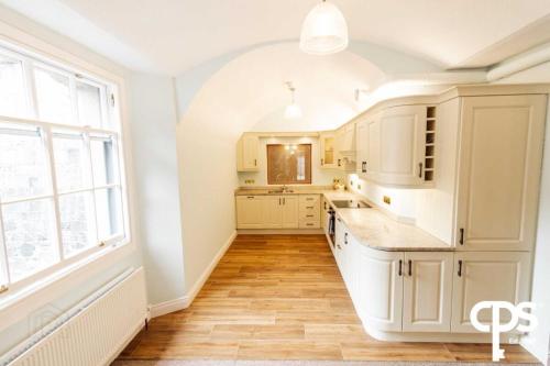 a kitchen with white cabinets and a large window at Bastian Gate Gosford Castle 