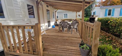 una terraza de madera con sillas y una mesa en una casa en Mobil-home de Ludo, en Ivry-la-Bataille