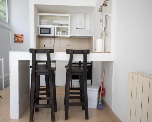 a kitchen with two wooden stools at a kitchen counter at Altos de Ventana in Sierra de la Ventana