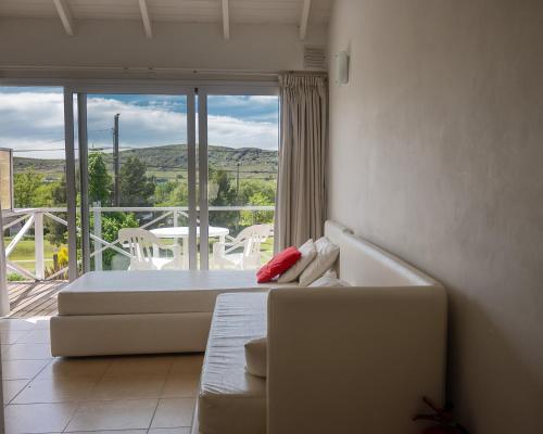 a room with a couch and a balcony with a table at Altos de Ventana in Sierra de la Ventana
