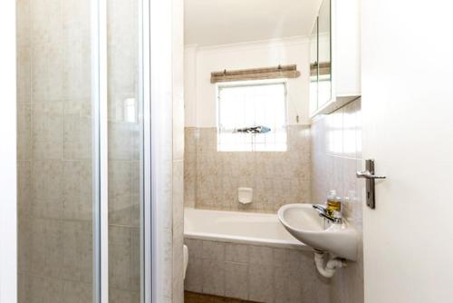 a bathroom with a tub and a sink and a shower at Sand Castle in Langebaan
