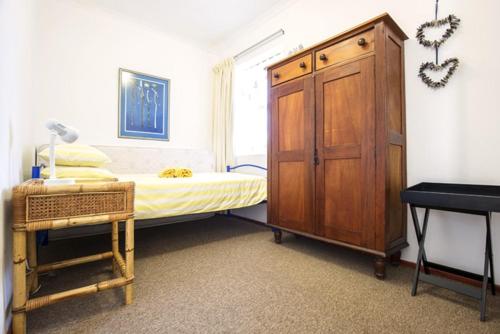 a bedroom with a bed with a wooden cabinet and a desk at Sand Castle in Langebaan