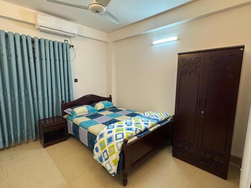 ein Schlafzimmer mit einem Bett und einem blauen Vorhang in der Unterkunft Maa in Dhaka