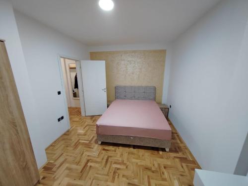 una camera da letto con un letto e un pavimento in legno di Apartman GOBATE a Požarevac