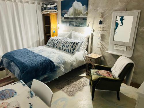 a bedroom with a bed and a chair at the Lighthouse Beachroom in Cape Town