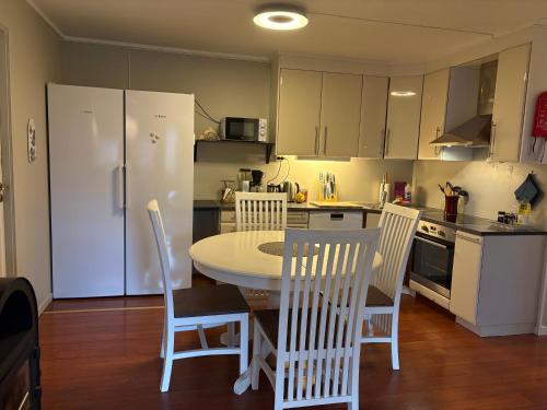 a kitchen with a table and chairs and a white refrigerator at Lillian's gjestehus, Skibotn in Skibotn