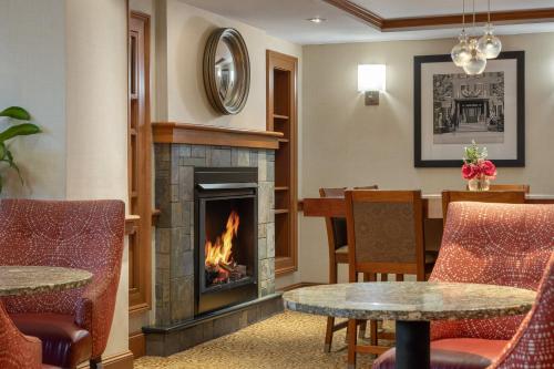 a fireplace in a living room with chairs and a table at Long Creek Hotel in South Portland