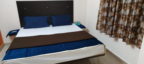 a bedroom with a bed with blue pillows at Guru Krupa Home Stay in Tiruvannāmalai