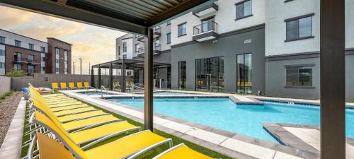a swimming pool with yellow chairs next to a building at Landing Amazing 1BD Gym Clubhouse in Phoenix