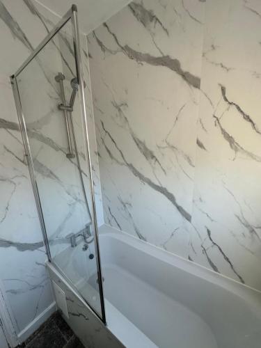 Un baño con ducha y una pared de mármol blanco. en Enfield Contractor Base With Games Room, en Brimsdown Station