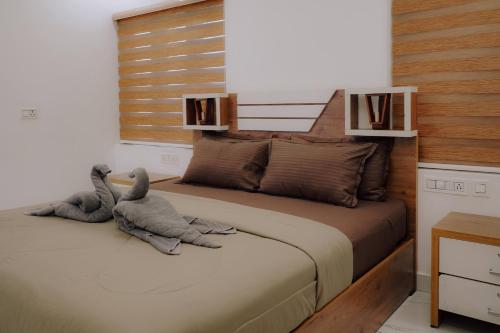 two stuffed animals sitting on a bed in a bedroom at The Kalt Private Pool Homestay Munnar in Anachal